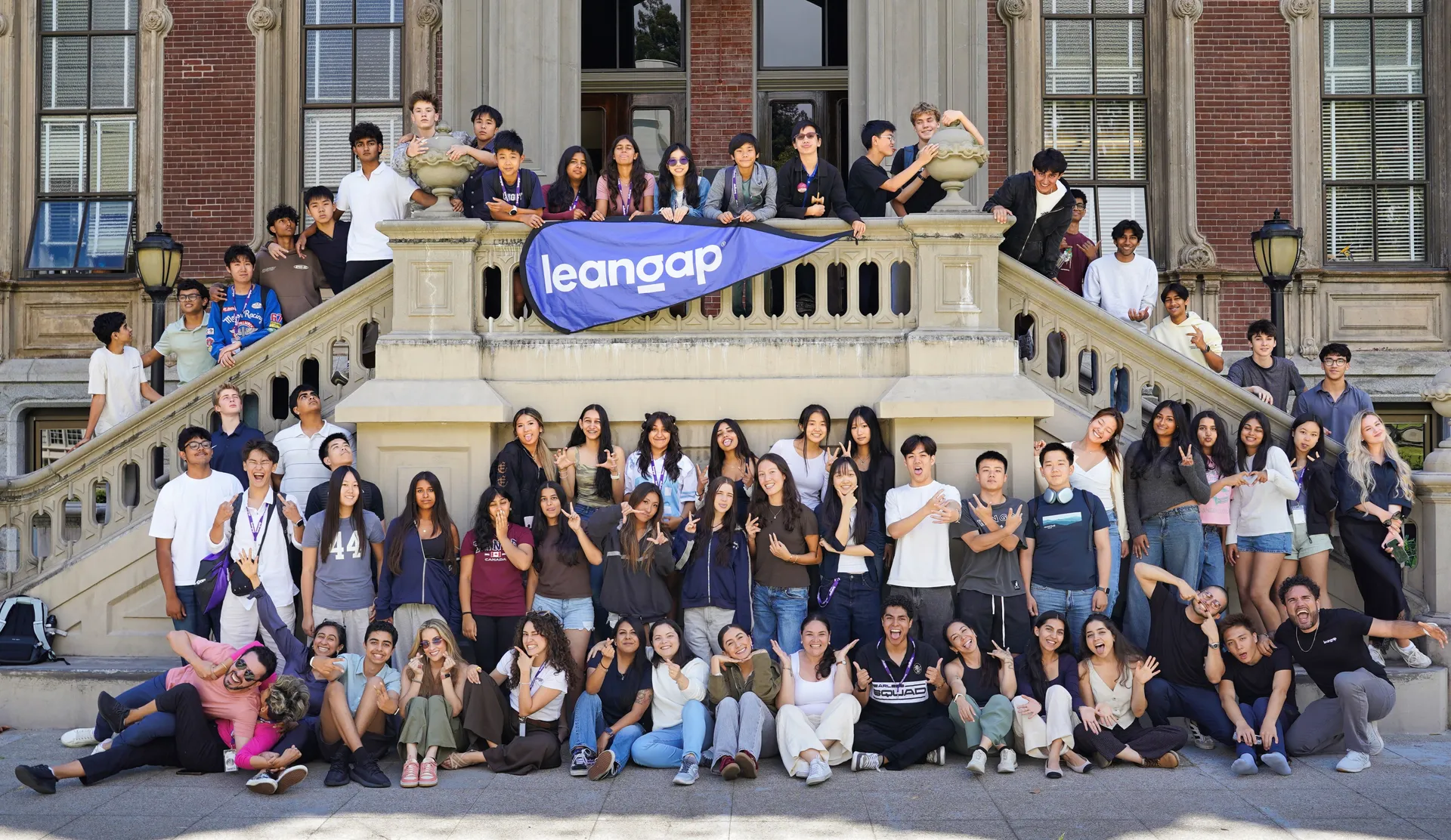 The Leangap students and team on the steps of a building at Berkeley, holding a Leangap banner