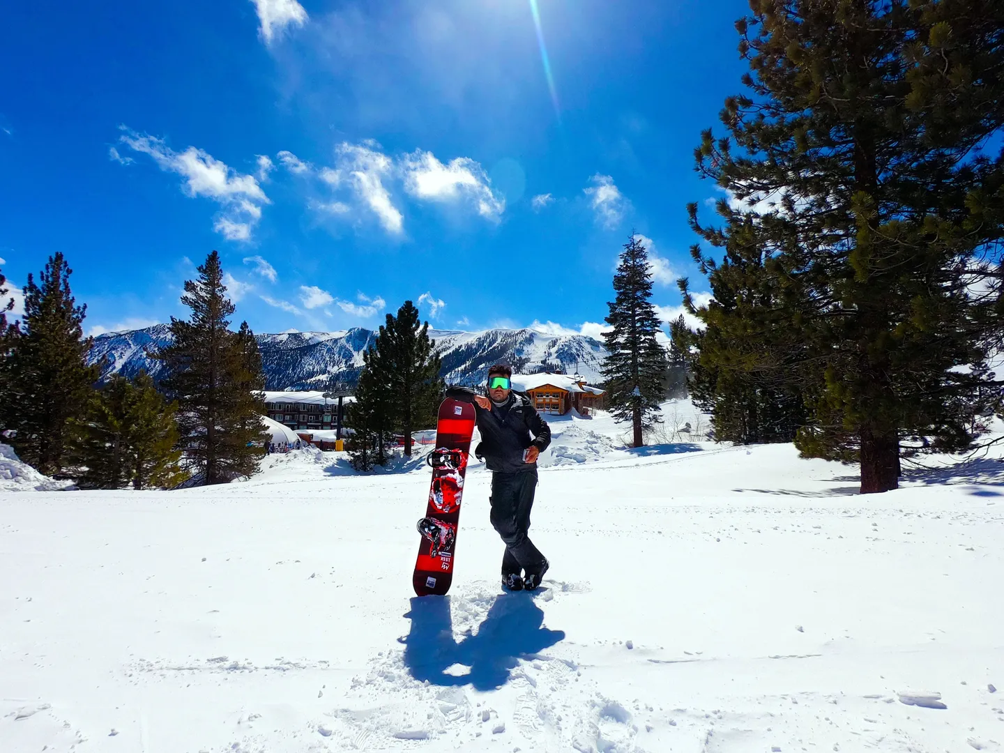 Sadok Cervantes with his snowboard on a sunny, snowy mountain