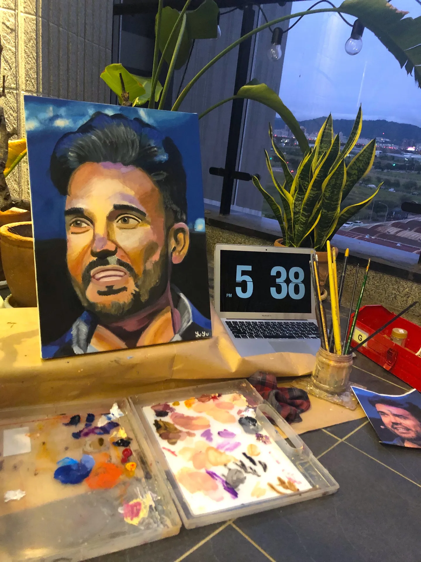 A painted portrait of Sadok Cervantes on an easel beside a paint palette