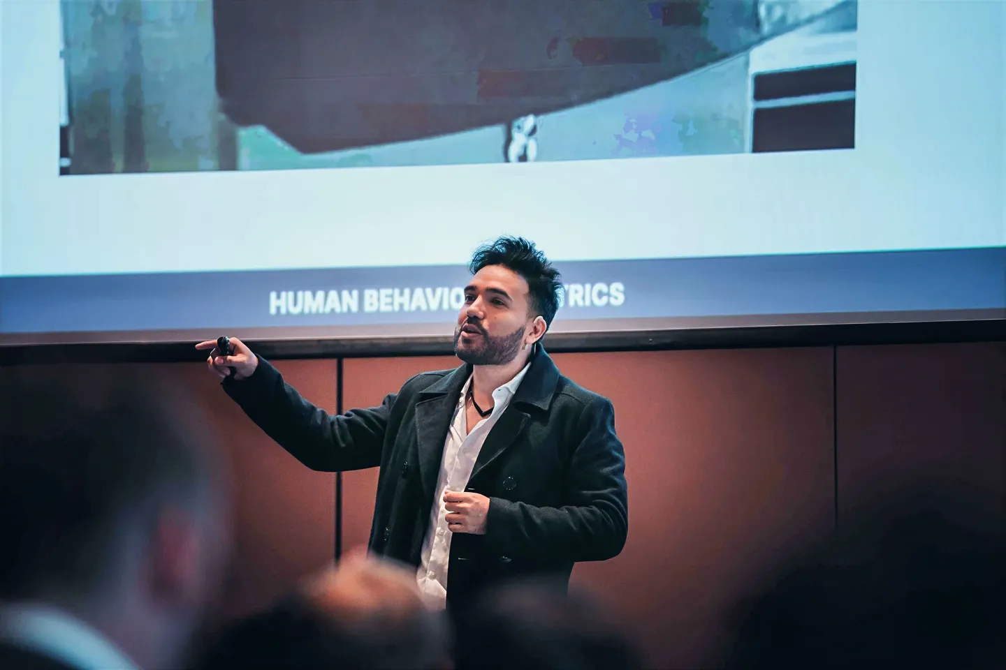 Sadok Cervantes on stage in front of a slide about human behavior