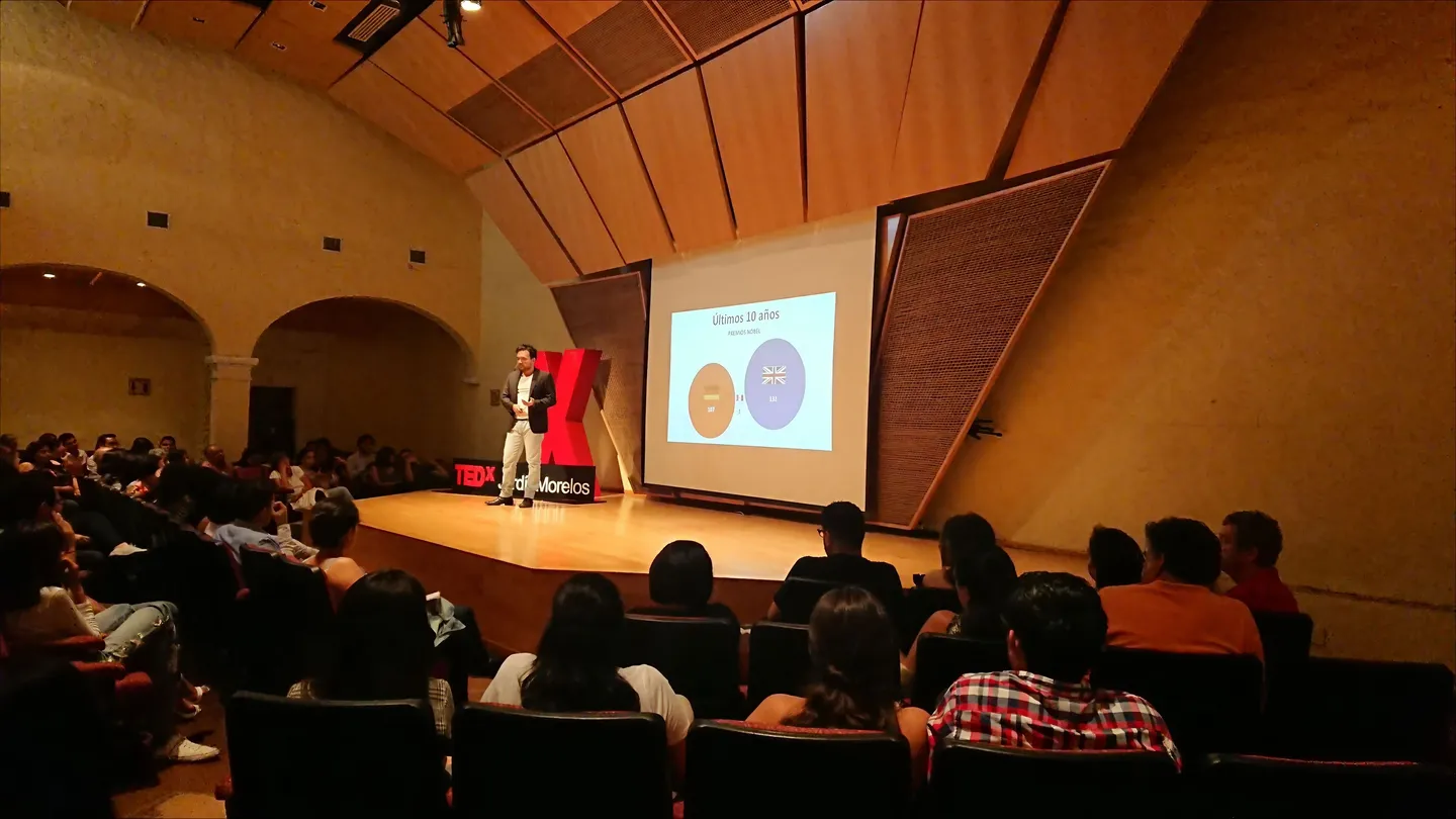 An audience in a wood paneled auditorium during a talk