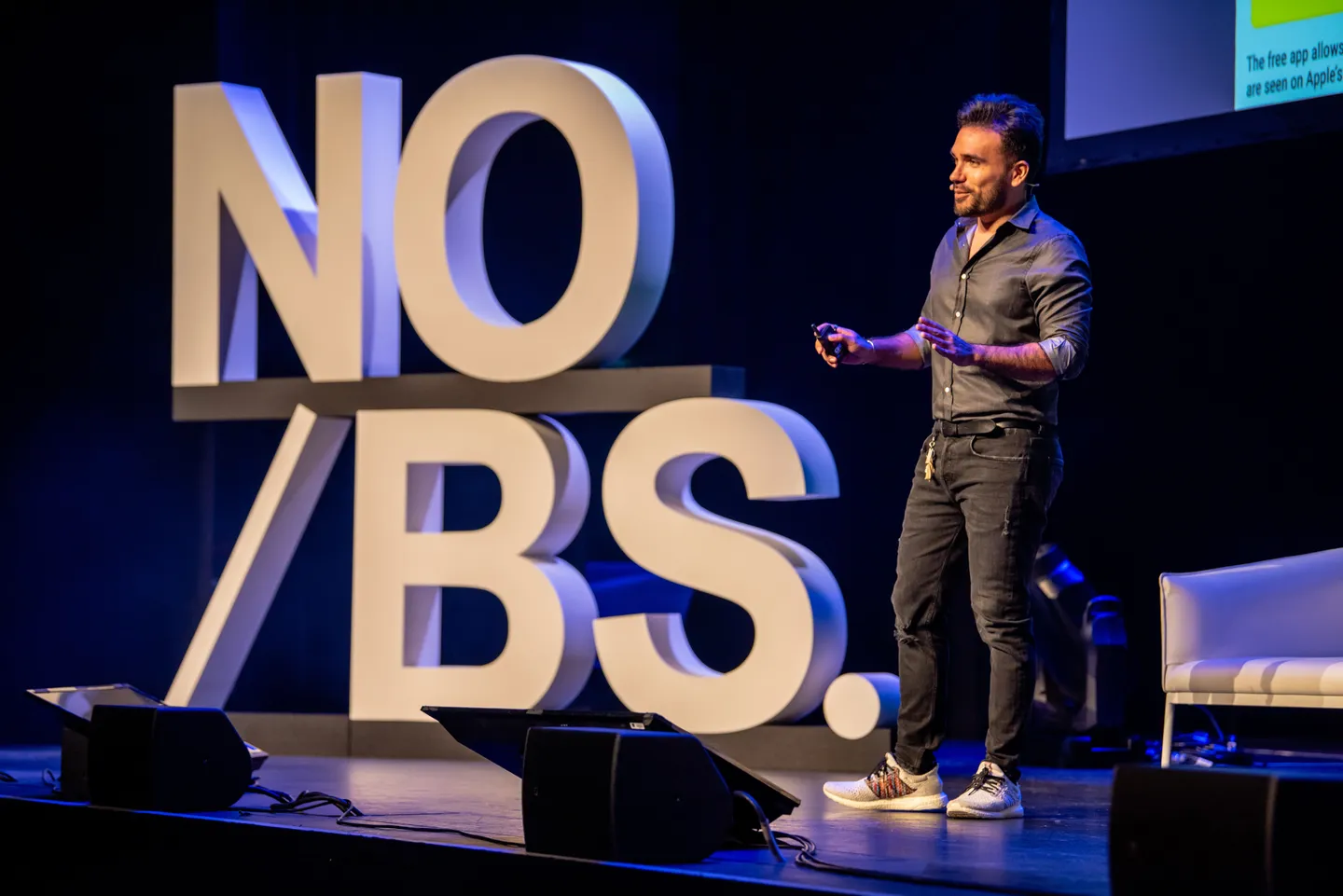 Sadok Cervantes on stage beside giant NO/BS. letters